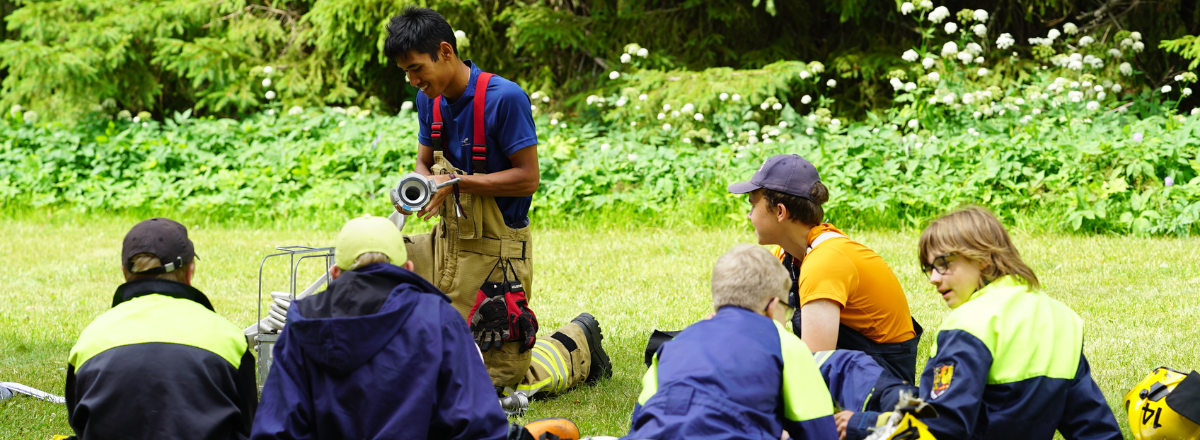 Palokuntanuoria kes&auml;leirill&auml; ja kouluttaja vet&auml;m&auml;ss&auml; koulutusta